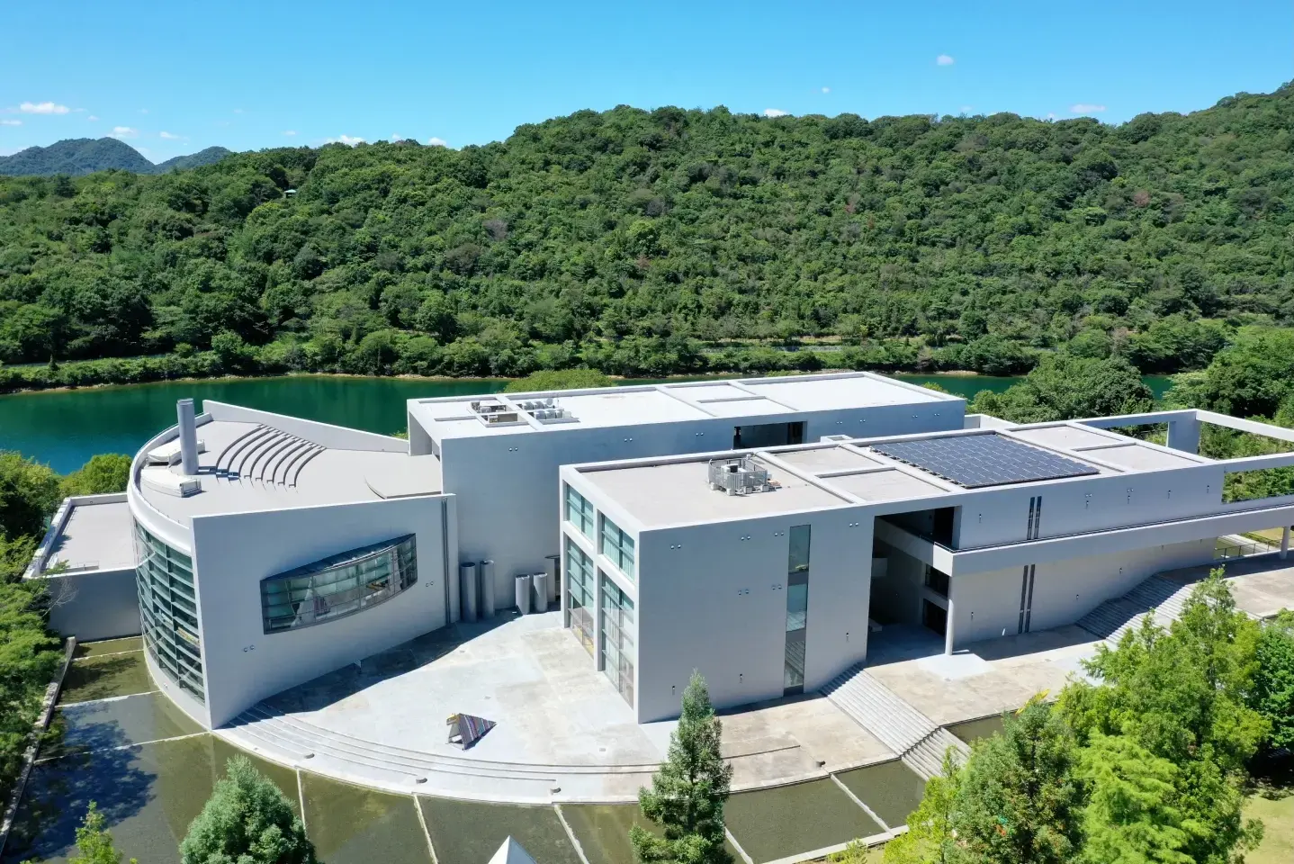 緑の山と湖に囲まれたこどもの館の建物を上空から見たようす
