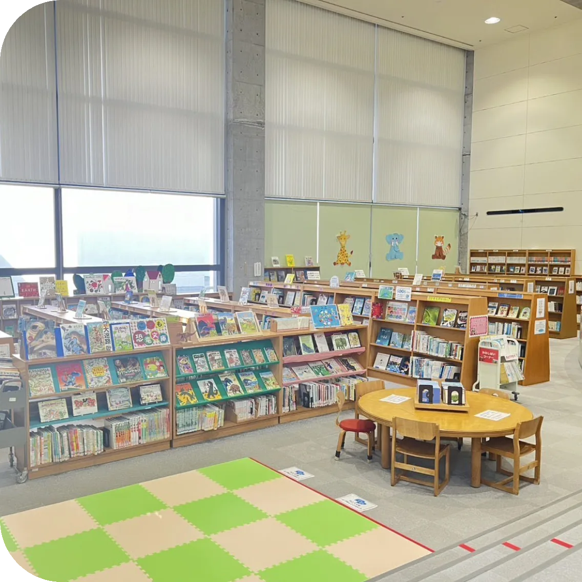 絵本が並ぶ本棚と丸いテーブルがある児童図書室のようす